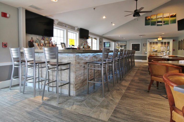 bar area with high stools and televisions playing golf